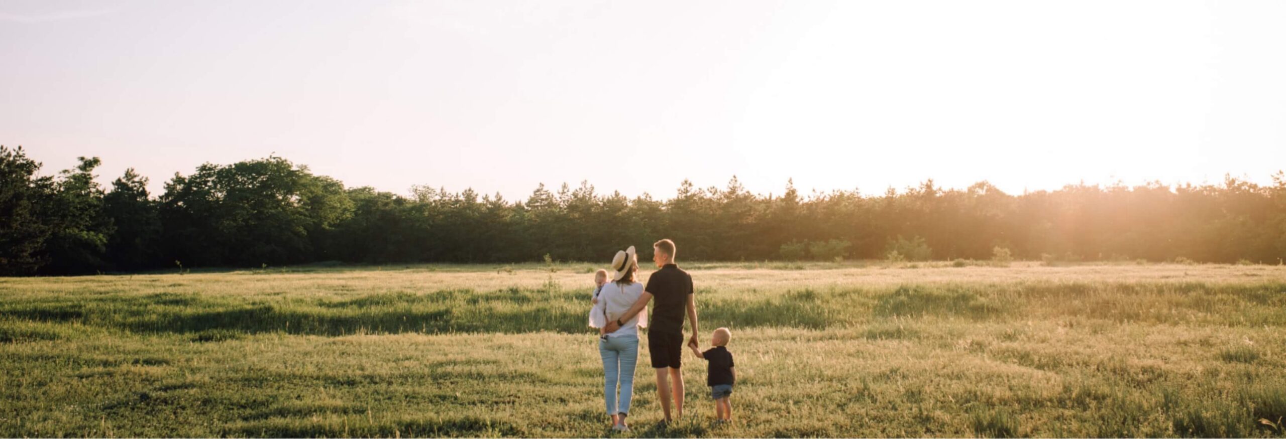 Couple with two kids holding hands in a field